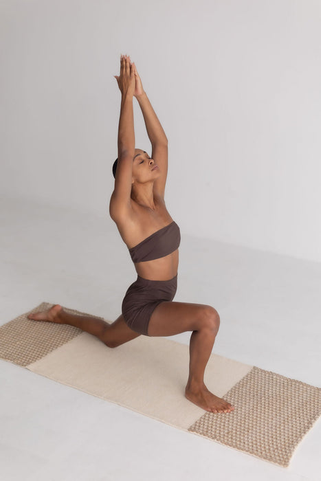 Person in a yoga pose on a mat with a plain background