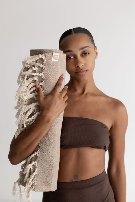 Woman holding a textured yoga mat against a plain background