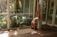 Person practicing yoga on a mat in front of a large window with greenery outside