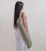 Woman holding a green yoga mat bag against a plain background