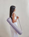 Woman holding a purple yoga mat bag against a plain background