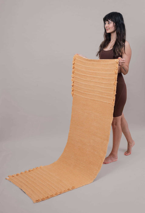 Woman holding up a yoga mat against a plain background