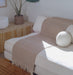 Beige yoga mat with tassles draped over a white sofa with a plant and decorative ball in the background.