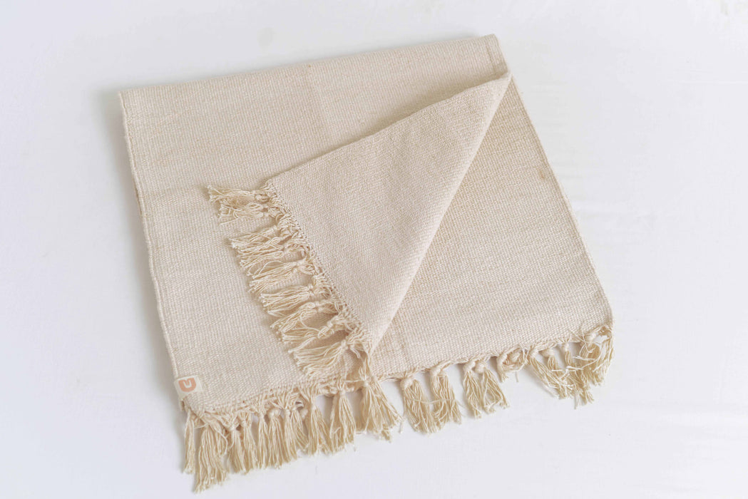 Beige woven yoga mat with fringes on a white background