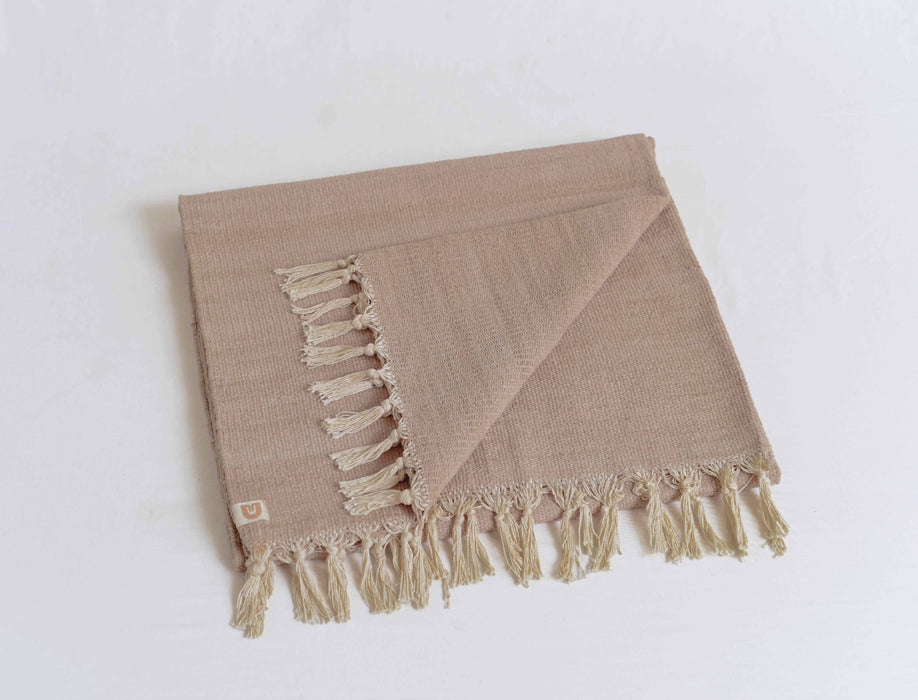 Beige woven yoga mat with tassels on a white background