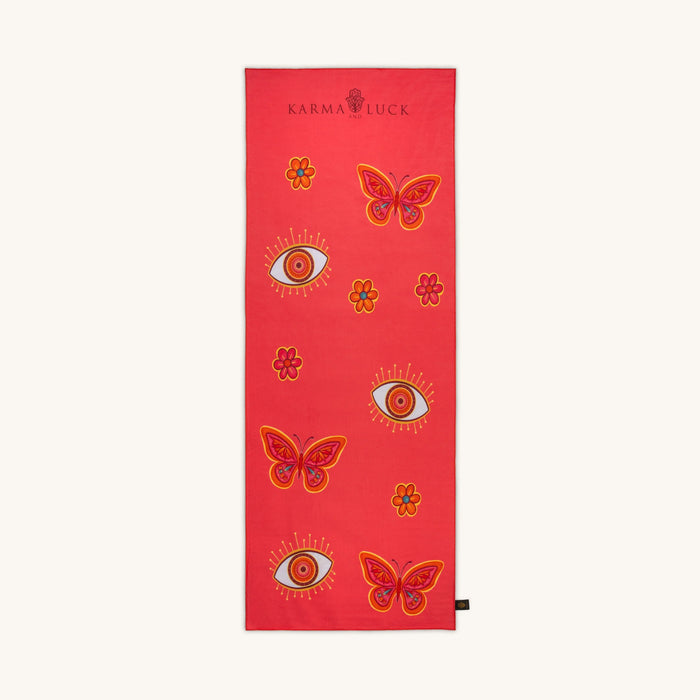 Red yoga mat with butterfly and eye designs on a white background