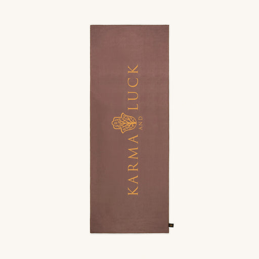 Brown yoga towel with 'Karma and Luck' logo on a white background