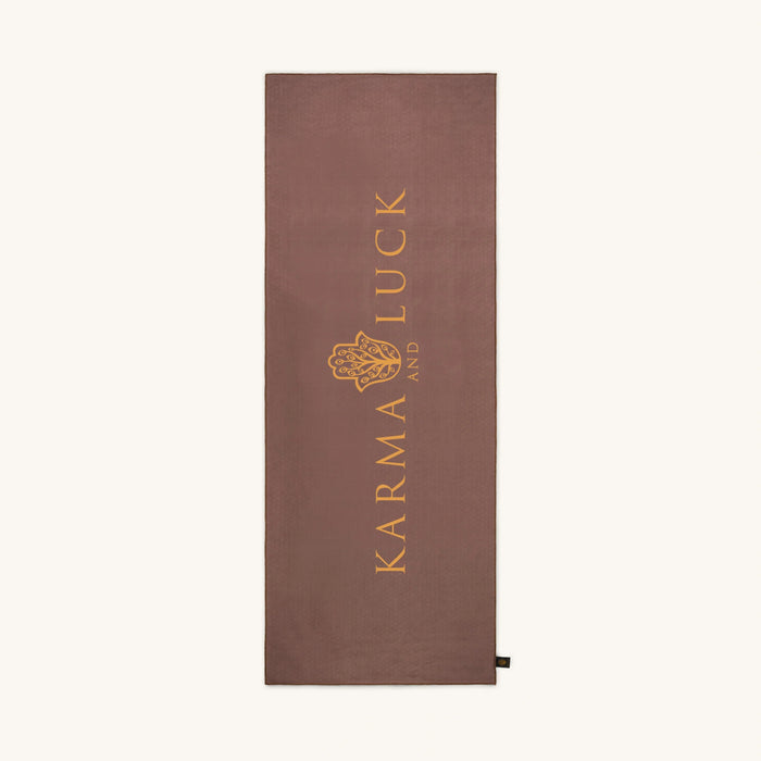 Brown yoga towel with 'Karma and Luck' logo on a white background