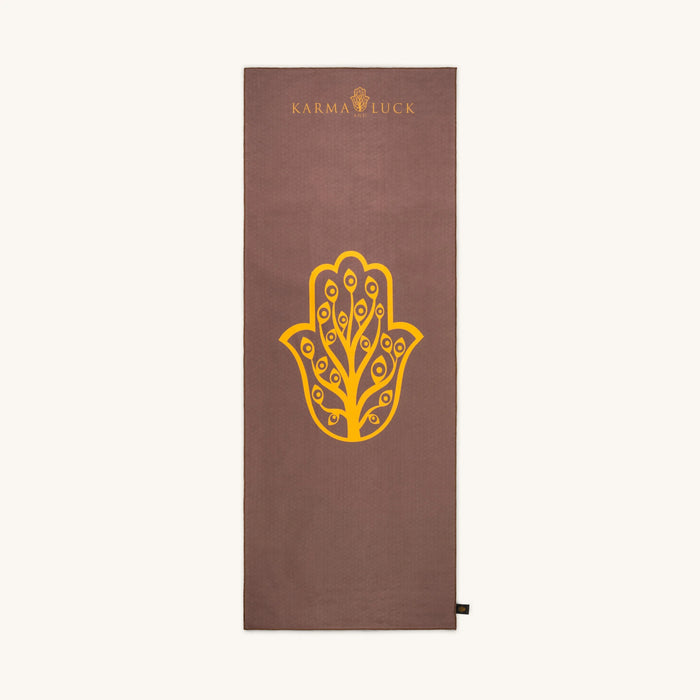 Brown yoga towel with yellow Hamsa hand design and 'Karma Luck' branding on a white background