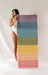Woman holding up a colorful yoga mat against a plain background