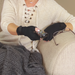 Person wearing black fingerless gloves holding a remote control on a couch.