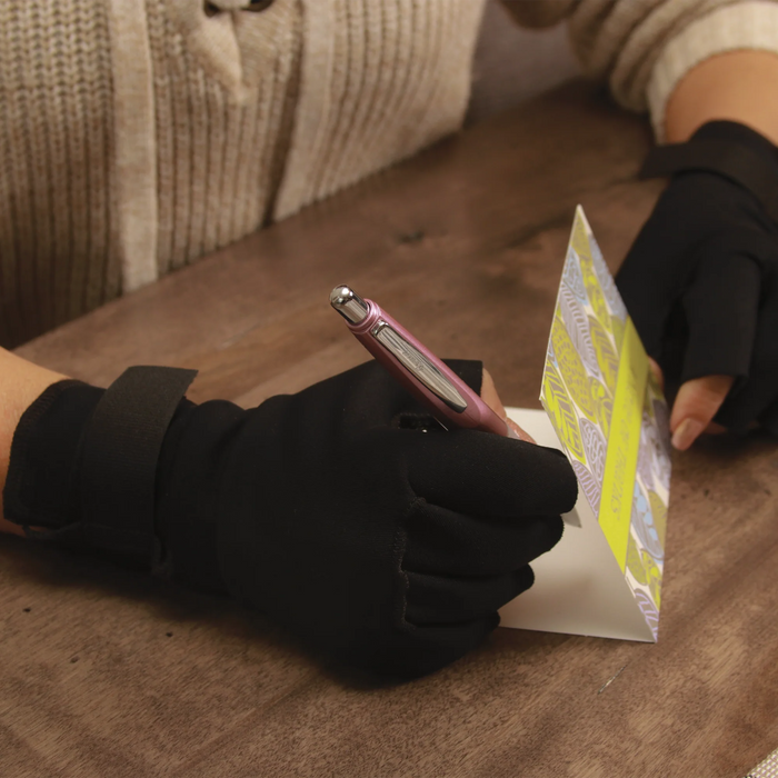 Person wearing black gloves holding a smartphone and a card on a wooden surface.